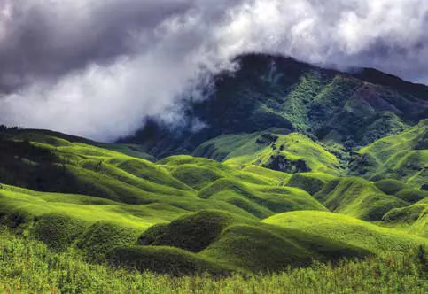 Rolling green hills in a valley under clouds