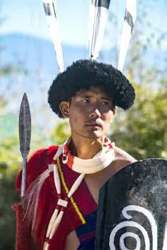 A man in a traditional Naga headdress holding a spear