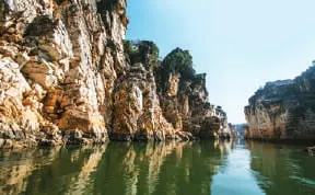 A boat on a river between white marble cliffs