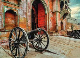 An old cannon on a wheeled carriage before a carved sandstone gateway
