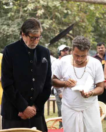Pankaj Jha, in white, signing a book beside Amitabh Bachchan