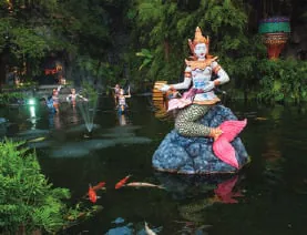 A mermaid statue in a garden pond