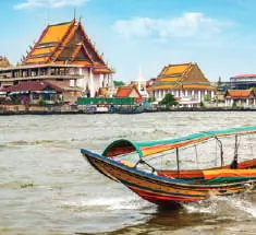 A longtail boat on the river in front of a temple