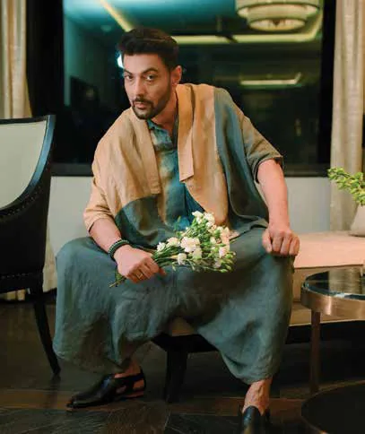 Ranveer Brar seated in a flowing green outfit, holding flowers