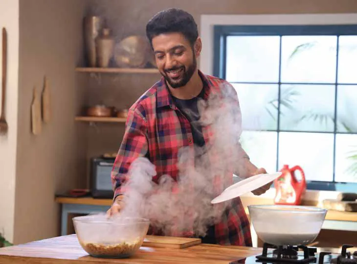 Ranveer Brar cooking at a stove as steam rises from a pot