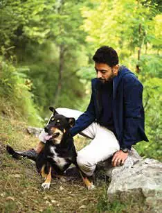 Ranveer Brar crouching beside a dog in a forest