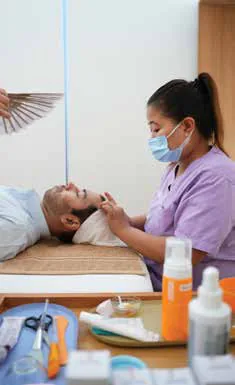 A man lying down as a technician treats his face