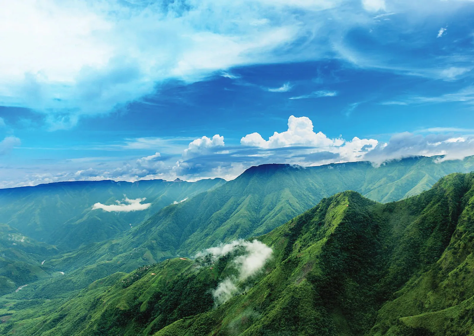 Green hills and valleys under a blue sky with clouds