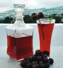 A glass of red wine beside a decanter and berries