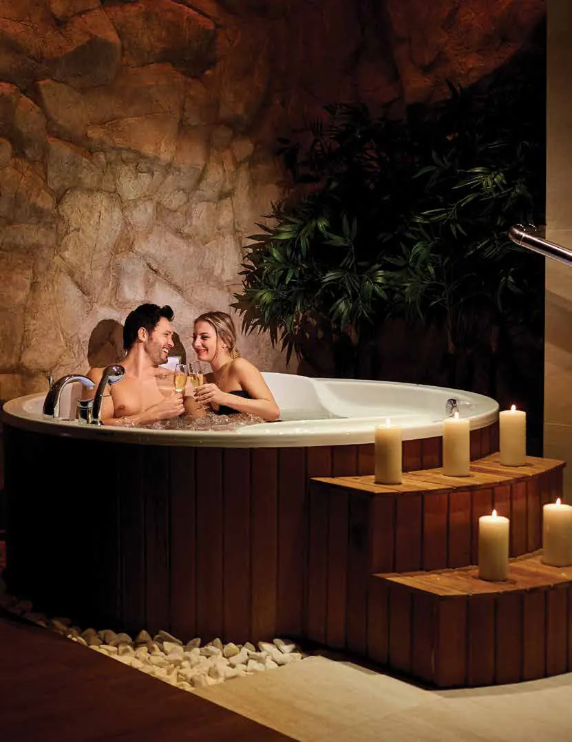 A couple relaxing in a candlelit hot tub
