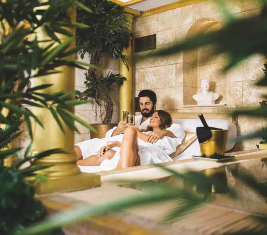 A couple in white robes relaxing in an ornate spa lounge