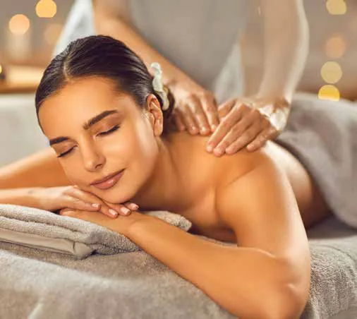 A woman lying on a massage table receiving a back massage