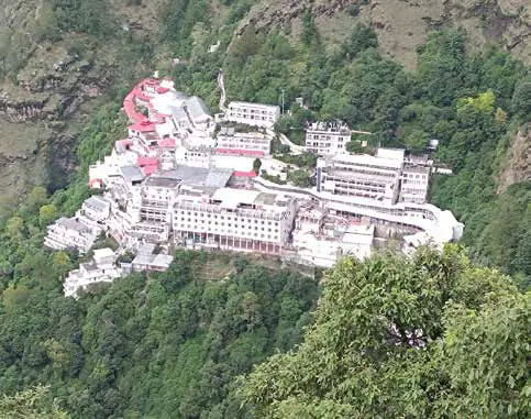 A white shrine complex built on a forested hillside
