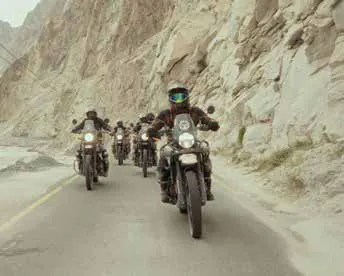 Motorcyclists riding along a road through a rocky valley
