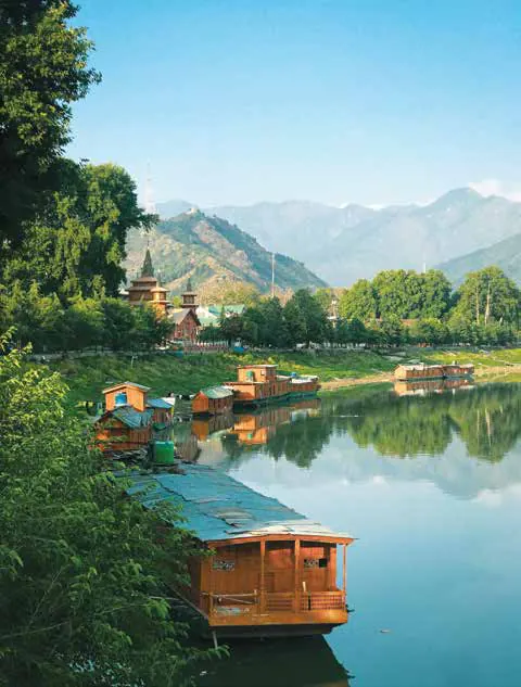 Houseboats moored on a calm lake below mountains