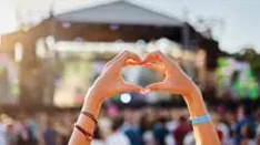 Hands forming a heart shape in front of a concert stage