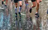 Runners splashing along a rain-soaked road
