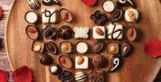 A heart of assorted chocolates on a wooden board