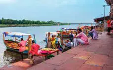 Boats moored at a riverside ghat, with people sitting on the steps