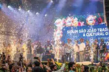 Performers on a festival stage under a shower of confetti