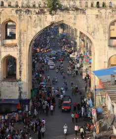 A crowded bazaar street seen through a stone archway