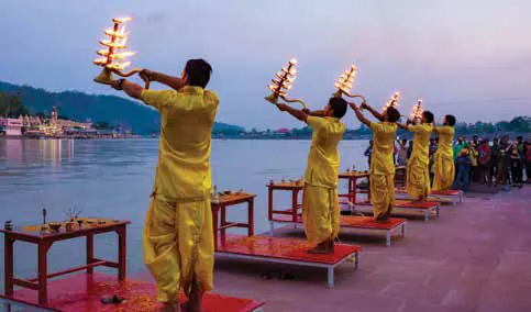 A row of priests holding up lamps during a riverside evening ritual