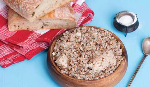 A bowl of buckwheat with bread rolls on a cloth