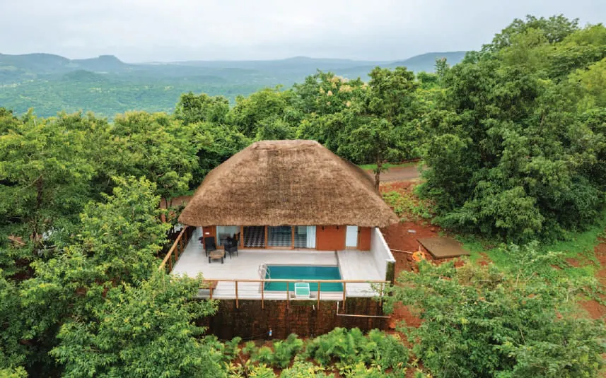 A thatched cottage with a pool among trees