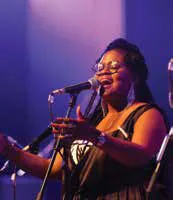 A jazz singer performing on stage in purple light