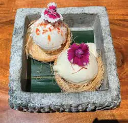A plated dessert decorated with flowers on a stone slab