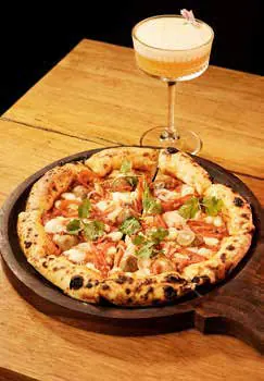 A pizza and a cocktail on a table