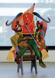 A colourful sculpture of a figure seated on a chair