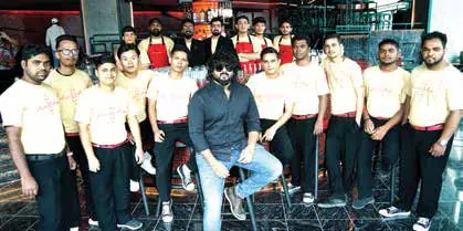 A restaurant team in matching cream uniforms posing together