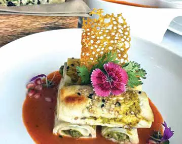 A plated dish garnished with a lace tuile and an edible flower