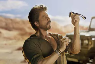 A man holding up a pair of sunglasses in a desert landscape