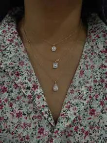 Layered pendant necklaces worn over a floral top