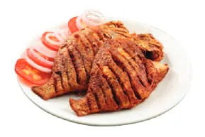 A plate of spiced grilled fish with onion and tomato slices