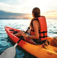 A woman kayaking at sunset